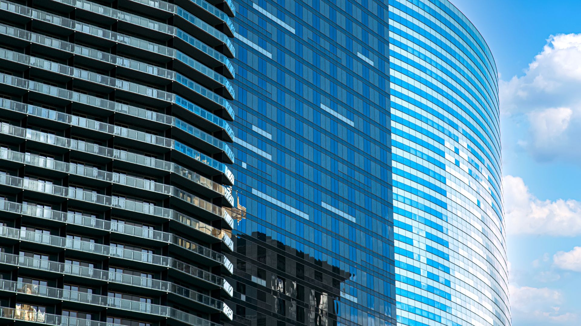 External view of a glass-sided skyscraper, reflecting the blue sky on a sunny day