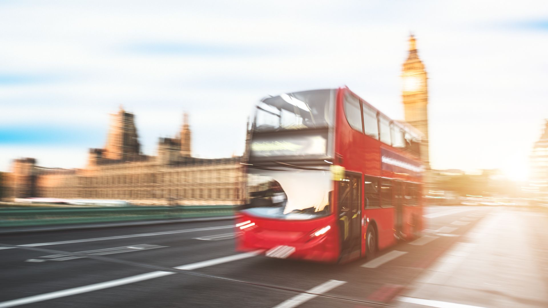 Blurry motion shot of a red London bus driving through the city past Big Ben and the Houses of Parliament